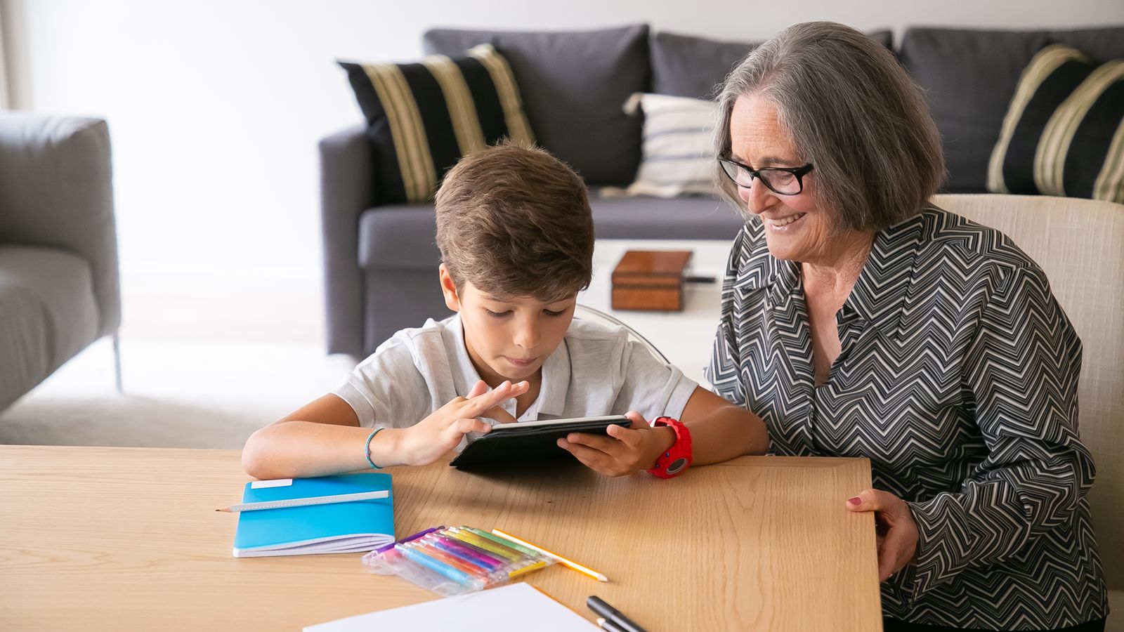 A grandmother and grandchild looking through a digital memory book together on a tablet