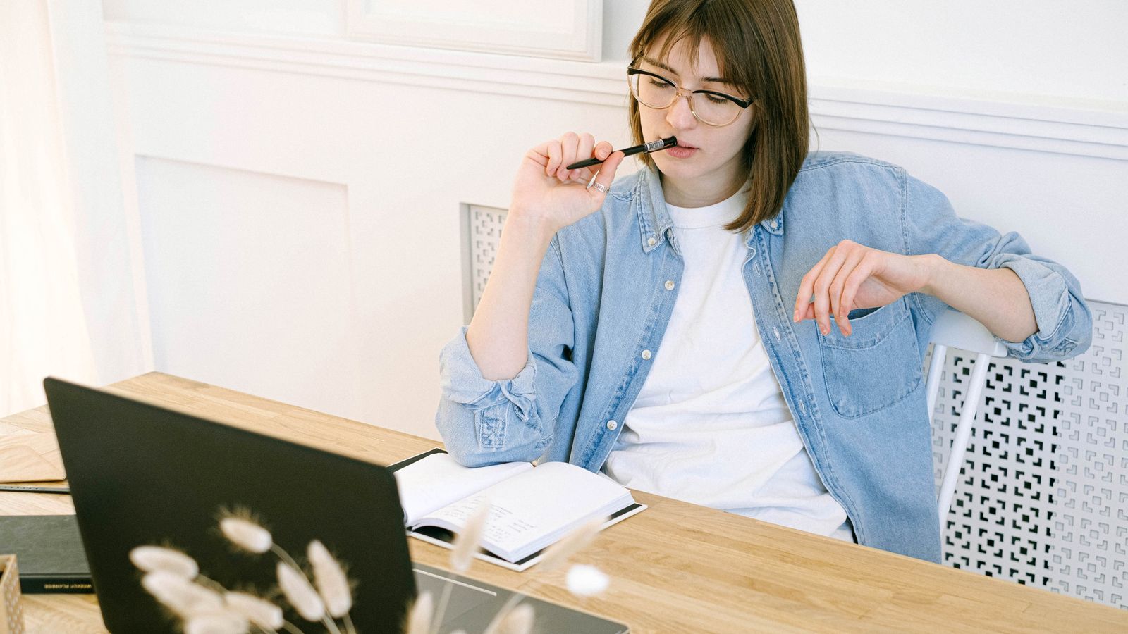 Woman planning a family history scrapbook at a bright desk with a laptop and an open notebook