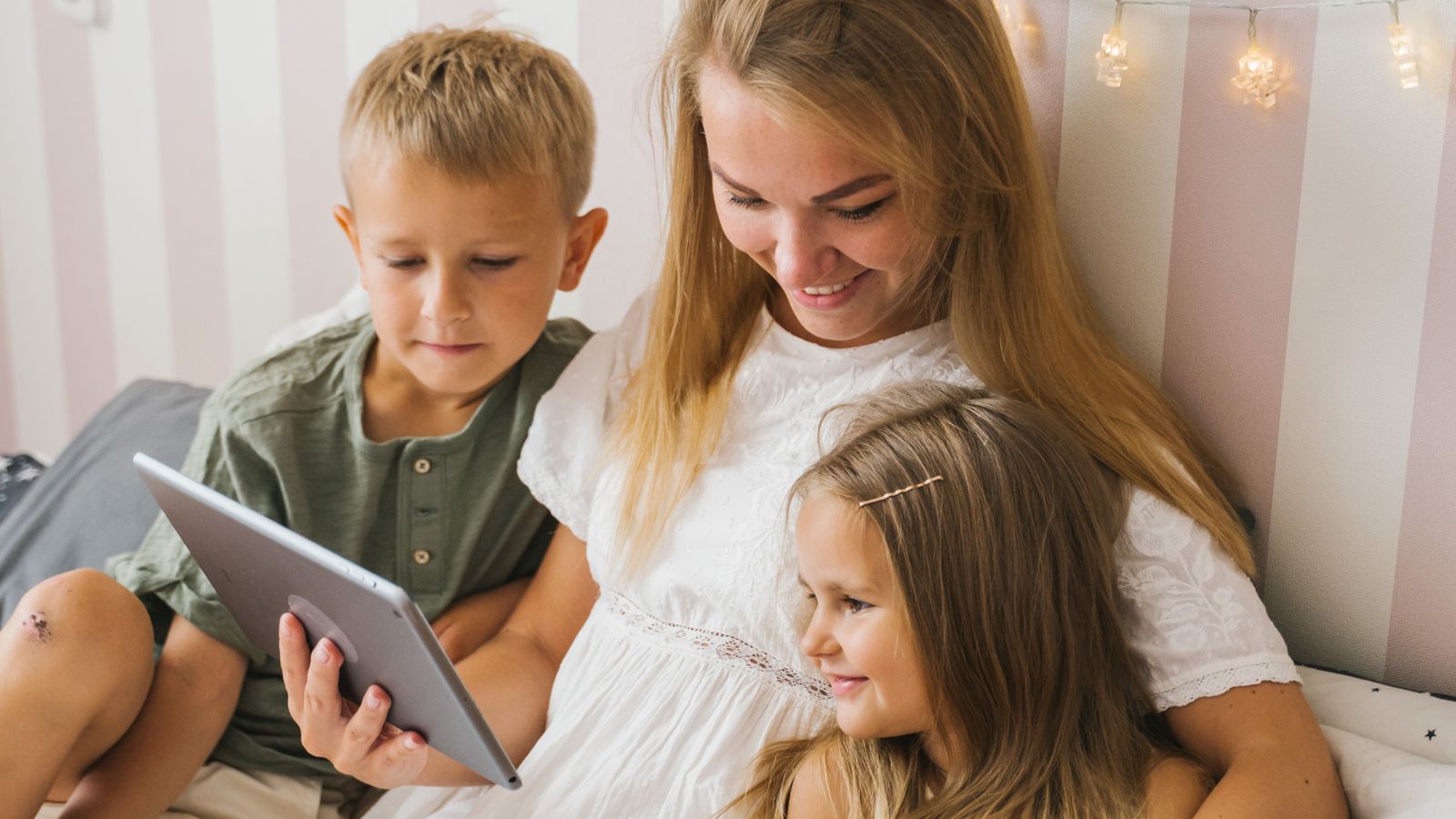Mother and two children looking at family photos together on a tablet at home