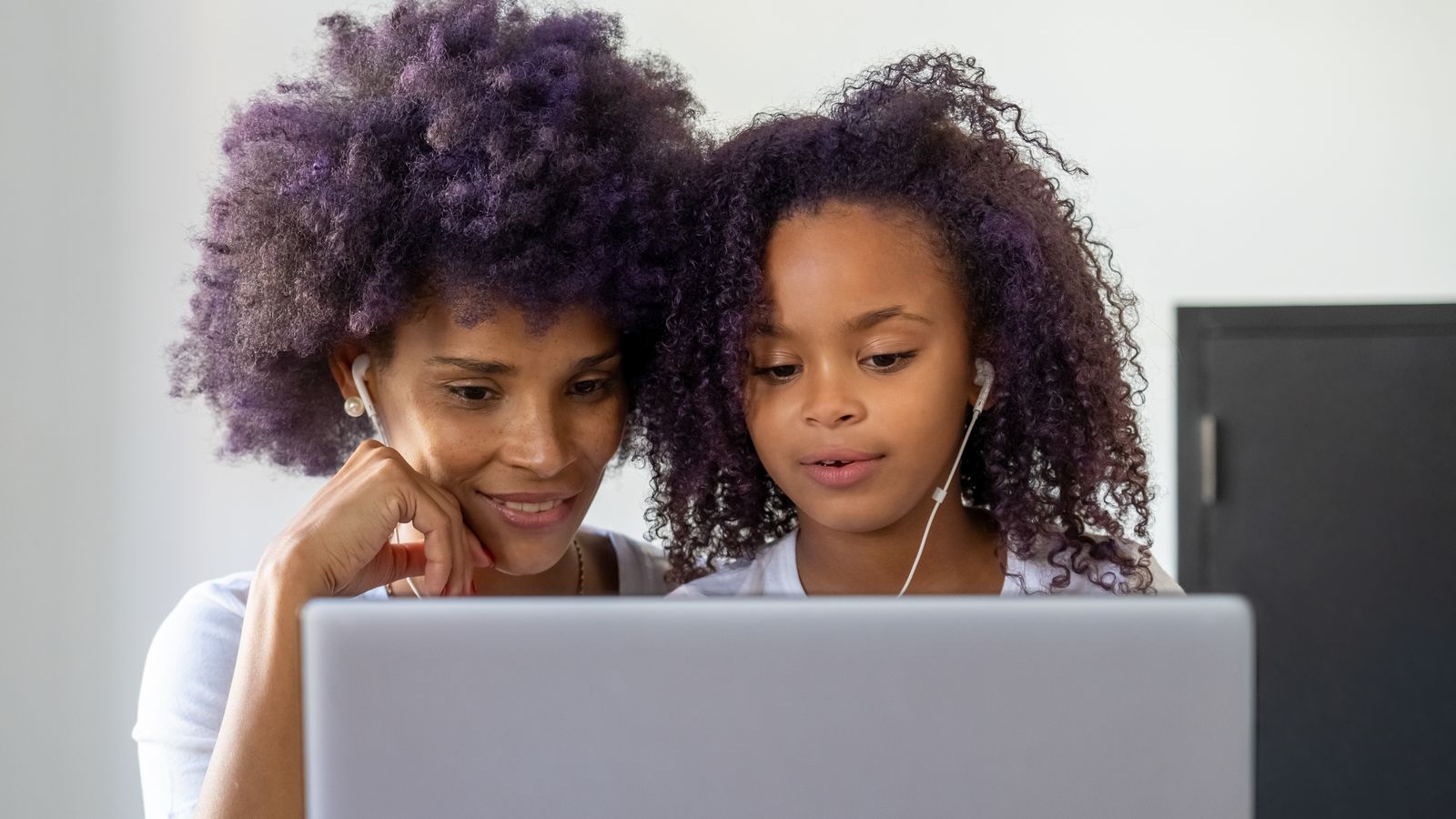 Woman and her daughter using a laptop together to make a scrapbook online at home