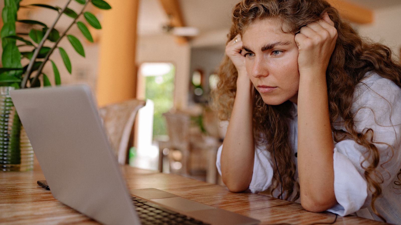 Woman using a vision board maker on a laptop in bright natural light